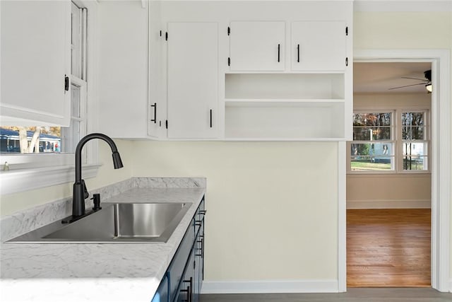 kitchen with white cabinets, hardwood / wood-style floors, ceiling fan, and sink