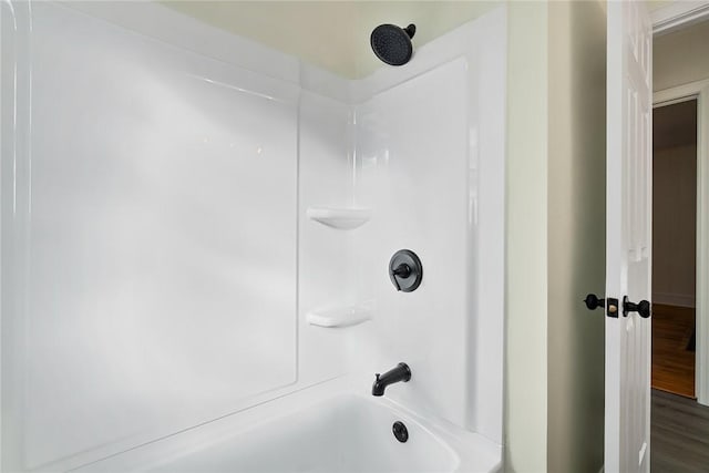 bathroom with wood-type flooring and washtub / shower combination