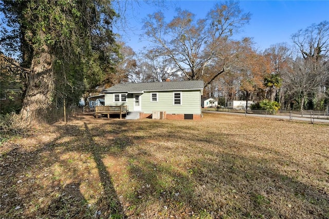 rear view of house featuring central air condition unit, a deck, and a lawn