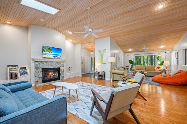 living room with ceiling fan, wooden ceiling, light hardwood / wood-style flooring, a fireplace, and vaulted ceiling with skylight