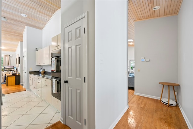 corridor with ornamental molding, light hardwood / wood-style flooring, and wooden ceiling