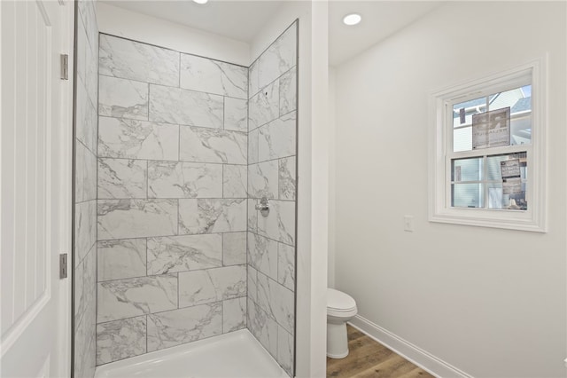 bathroom featuring hardwood / wood-style flooring, toilet, and tiled shower