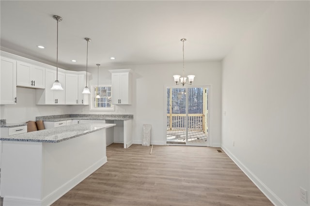 kitchen with light wood-type flooring, an inviting chandelier, white cabinetry, and a kitchen island