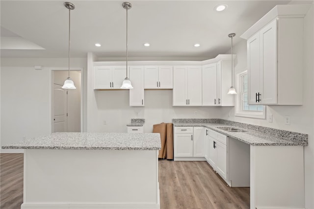 kitchen featuring white cabinetry, light hardwood / wood-style flooring, a kitchen island, and pendant lighting