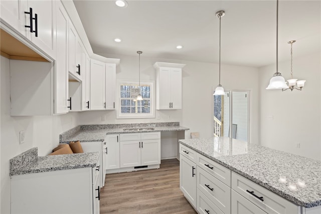 kitchen featuring white cabinetry, light hardwood / wood-style flooring, pendant lighting, and sink