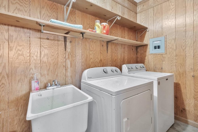 clothes washing area featuring sink, wooden walls, and washing machine and clothes dryer