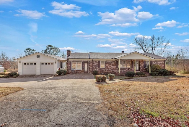 single story home featuring an outbuilding, a garage, and a front lawn