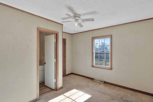 unfurnished bedroom with ceiling fan, light colored carpet, a textured ceiling, and ornamental molding