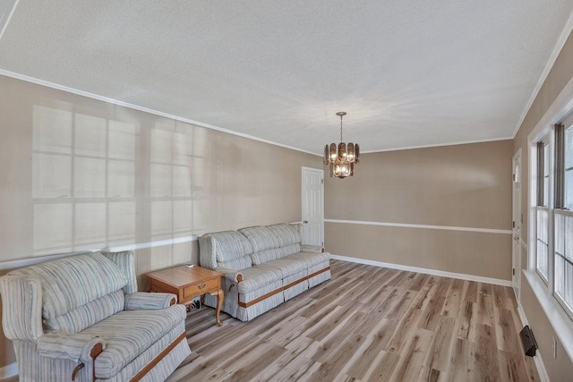 sitting room with plenty of natural light, light wood-type flooring, ornamental molding, and an inviting chandelier