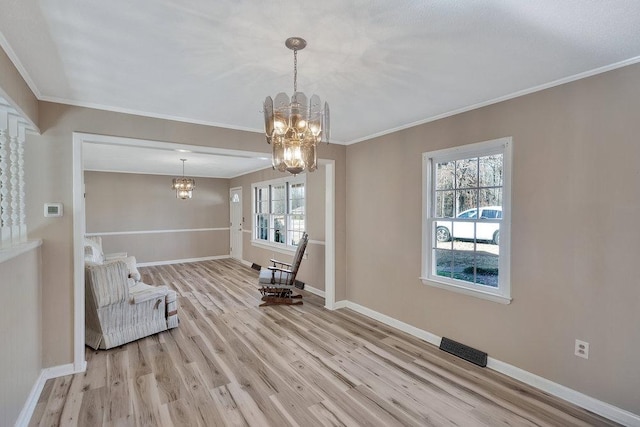 unfurnished room with a chandelier, crown molding, and light hardwood / wood-style floors