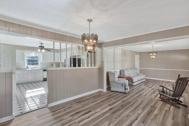 living room featuring a textured ceiling, ceiling fan with notable chandelier, light hardwood / wood-style floors, and crown molding