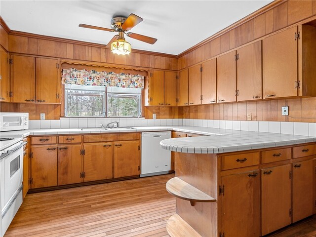 kitchen featuring ceiling fan, sink, tile countertops, light hardwood / wood-style floors, and white appliances