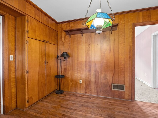 spare room with wood walls, crown molding, and light hardwood / wood-style floors