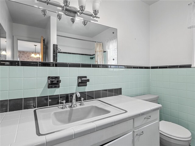 bathroom with vanity, toilet, and tile walls