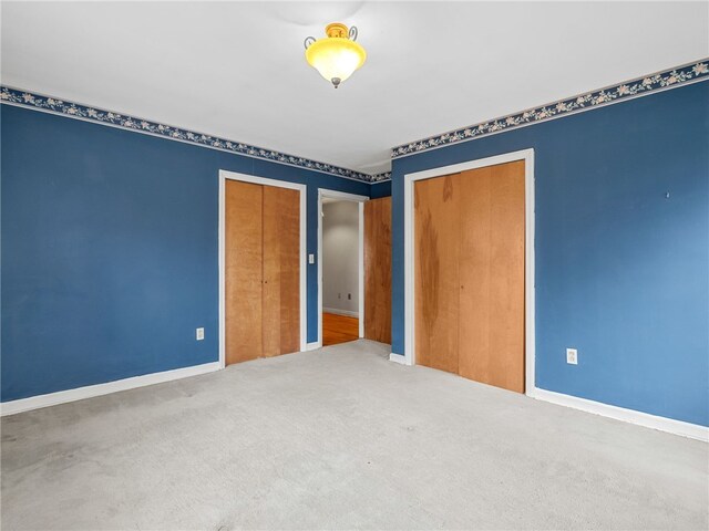 unfurnished bedroom featuring carpet flooring and multiple closets