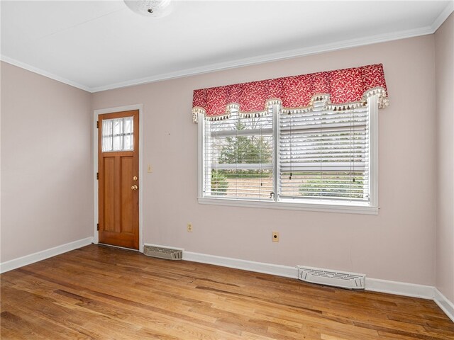 entrance foyer featuring hardwood / wood-style floors, a wealth of natural light, and crown molding