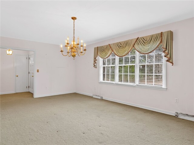 carpeted empty room with an inviting chandelier