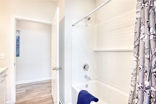 bathroom with shower / bathtub combination with curtain, hardwood / wood-style floors, and vanity