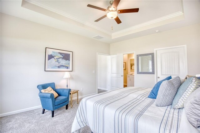 carpeted bedroom with crown molding, ceiling fan, a raised ceiling, and ensuite bath