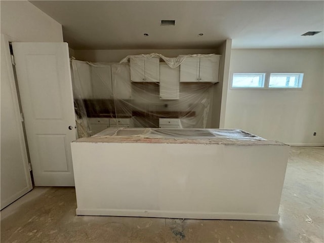 kitchen with concrete floors, visible vents, and a center island