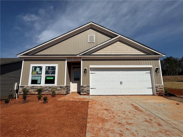 craftsman inspired home with an attached garage, stone siding, and driveway