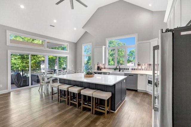 kitchen with a center island, stainless steel appliances, high vaulted ceiling, a kitchen bar, and white cabinets