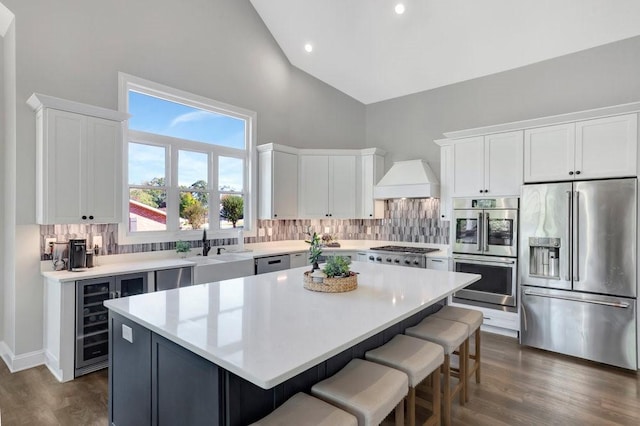 kitchen featuring white cabinetry, a center island, stainless steel appliances, high vaulted ceiling, and decorative backsplash