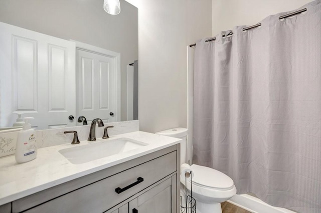 bathroom featuring a shower with shower curtain, vanity, and toilet