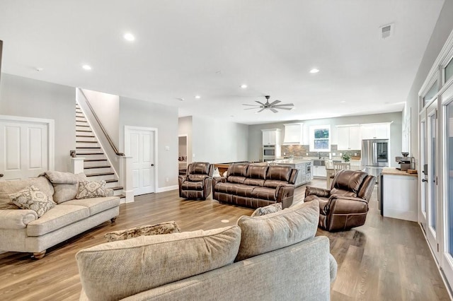 living room with light hardwood / wood-style floors and ceiling fan