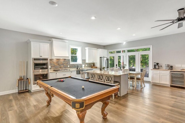 rec room with a healthy amount of sunlight, light wood-type flooring, billiards, and beverage cooler