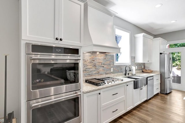 kitchen with white cabinets, appliances with stainless steel finishes, and custom exhaust hood