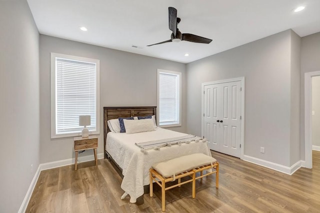 bedroom with ceiling fan, a closet, wood-type flooring, and multiple windows