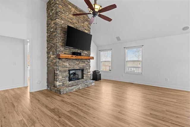 unfurnished living room featuring a stone fireplace, ceiling fan, high vaulted ceiling, and light hardwood / wood-style floors