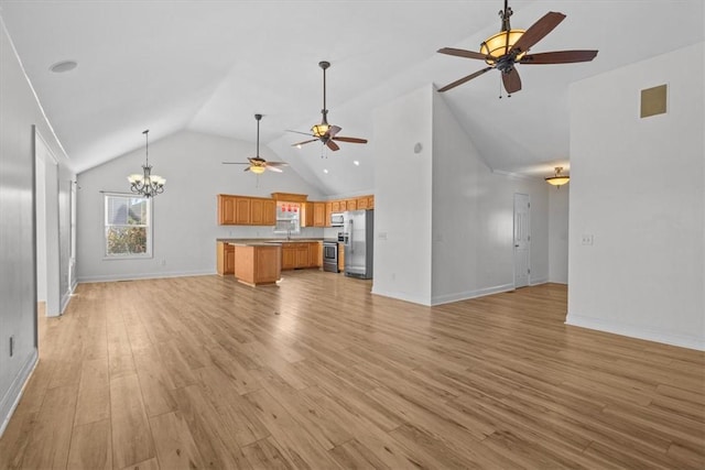 unfurnished living room featuring ceiling fan with notable chandelier, lofted ceiling, sink, and light hardwood / wood-style flooring