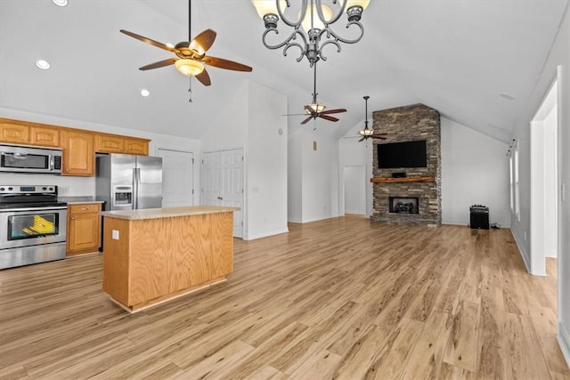 kitchen featuring a stone fireplace, a kitchen island, lofted ceiling, and appliances with stainless steel finishes