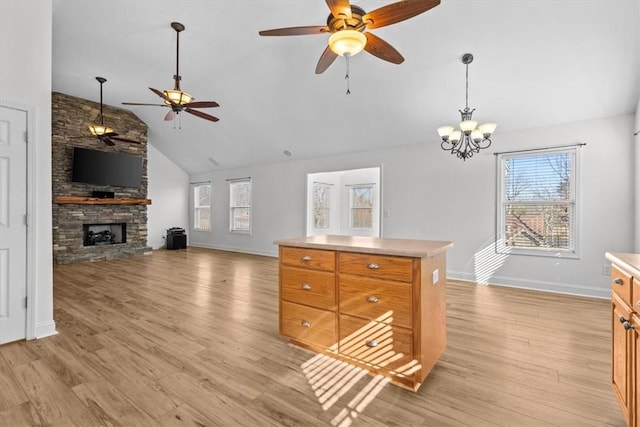 living room featuring vaulted ceiling, a fireplace, light hardwood / wood-style floors, and ceiling fan with notable chandelier