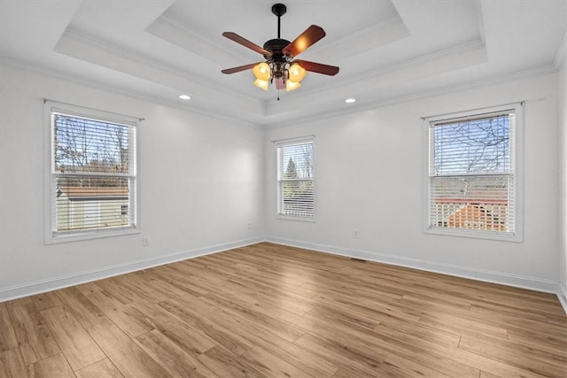 empty room with ceiling fan, a healthy amount of sunlight, a raised ceiling, and ornamental molding