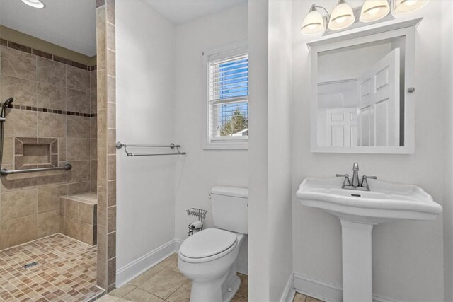 bathroom with tile patterned floors, sink, toilet, and tiled shower