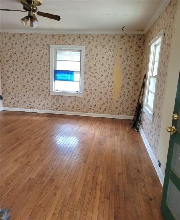 empty room featuring wood-type flooring, ceiling fan, and crown molding