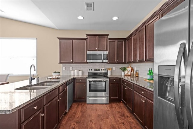 kitchen with light stone countertops, stainless steel appliances, and sink