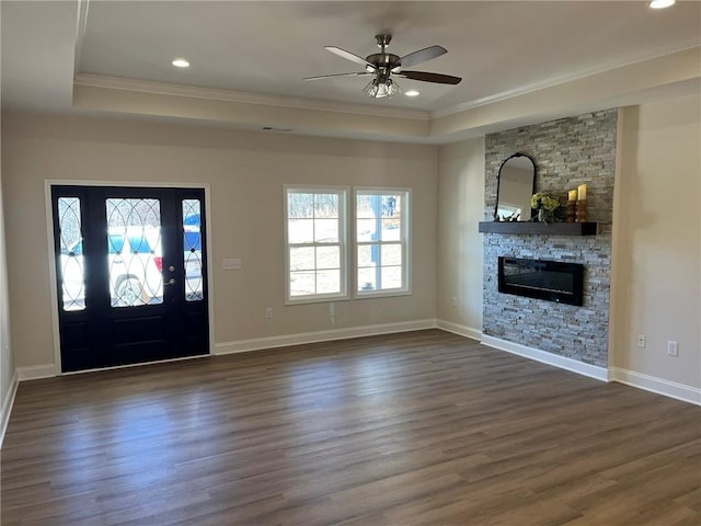 foyer with a fireplace, dark hardwood / wood-style flooring, a raised ceiling, and ceiling fan