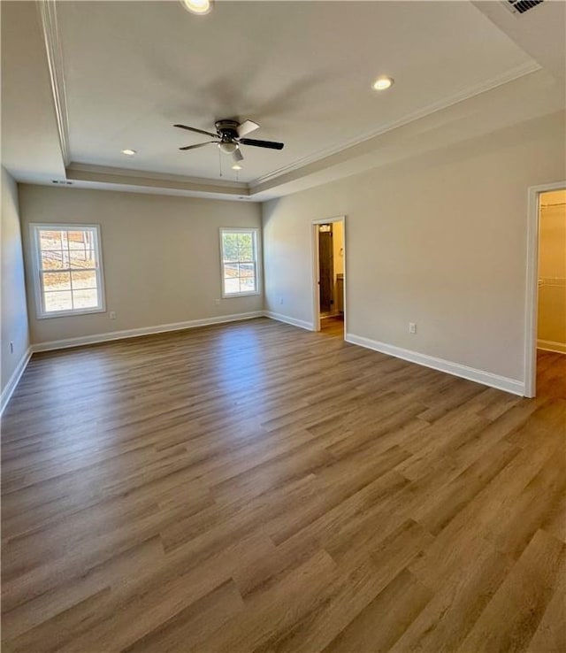 unfurnished room with ceiling fan, a raised ceiling, wood-type flooring, and ornamental molding