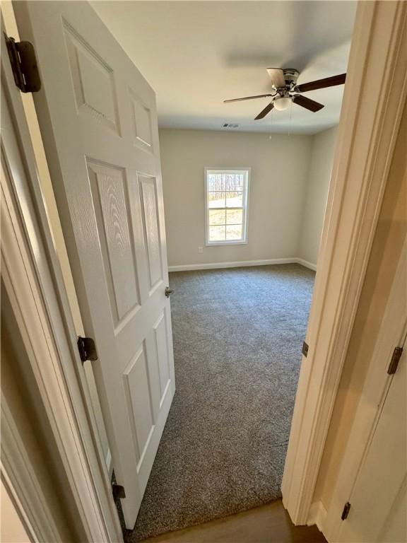 unfurnished room with ceiling fan and carpet