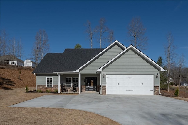 view of front of property with a garage, concrete driveway, covered porch, and stone siding