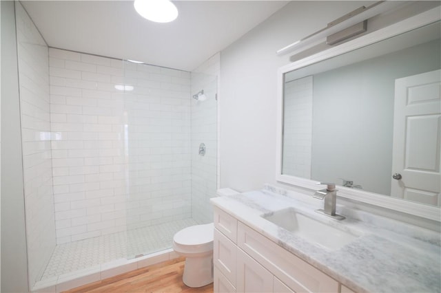 bathroom featuring tiled shower, toilet, vanity, and hardwood / wood-style flooring