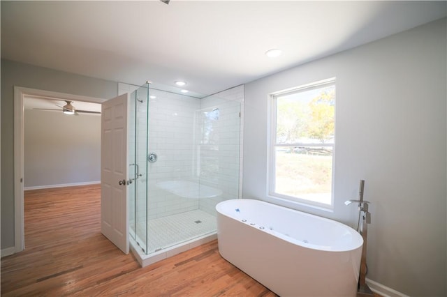 bathroom featuring plus walk in shower, hardwood / wood-style flooring, and ceiling fan