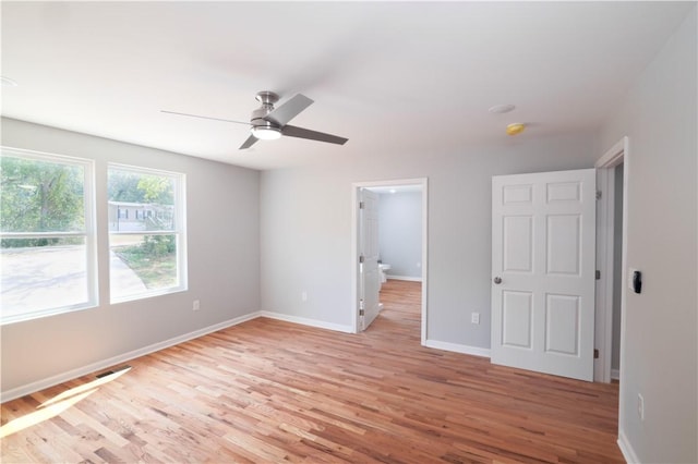 unfurnished bedroom featuring ceiling fan, light hardwood / wood-style floors, and a walk in closet