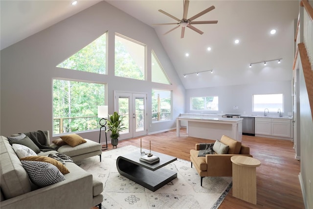 living room with ceiling fan, french doors, sink, high vaulted ceiling, and light hardwood / wood-style floors