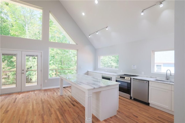 kitchen featuring white cabinetry, sink, a center island, light stone countertops, and appliances with stainless steel finishes