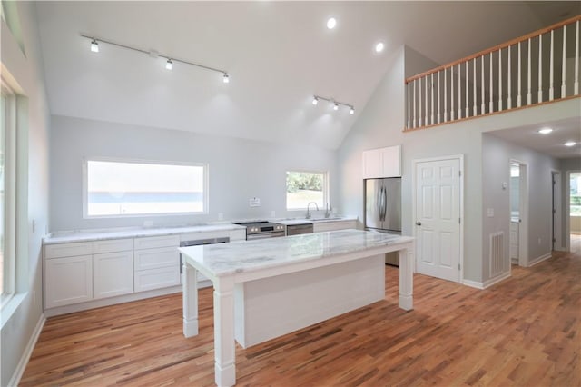 kitchen with a breakfast bar, white cabinets, light hardwood / wood-style floors, a kitchen island, and stainless steel appliances